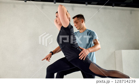 Professional fitness instructor guiding woman during training session 128714239