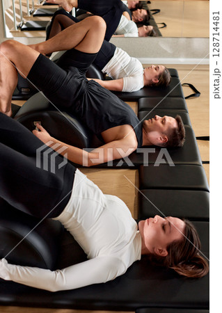 Group fitness training session focusing on core exercises on floor equipment 128714481
