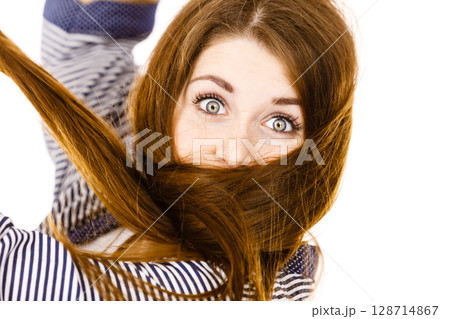 Woman having face covered with her brown hair 128714867
