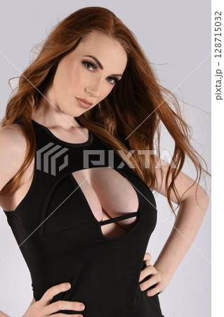 Beautiful, tall, redhead model wearing a revealing black dress and leather boots Beautiful, tall, redhead model wearing a revealing black dress and leather boots 128715032