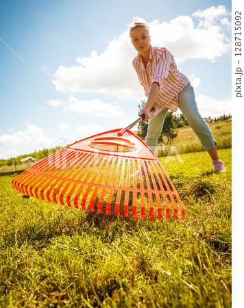 Unusual angle of woman raking leaves 128715092