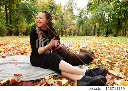 Woman enjoying a joyful moment with her dog in an autumn park Woman enjoying a joyful moment with her dog in an autumn park 128715189
