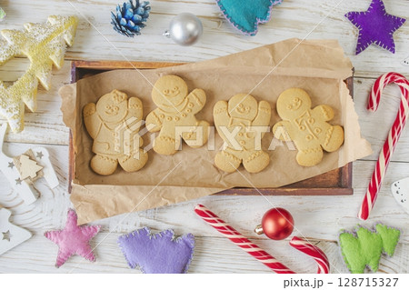 Christmas gingerbread cookies in the shape of a snowman on a white wooden background. Christmas decorations. Top view, flat lay. 128715327