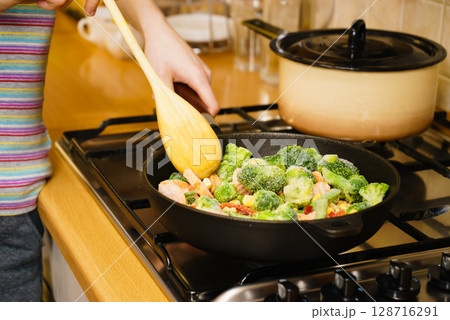 Girl frying vegetables on pan 128716291