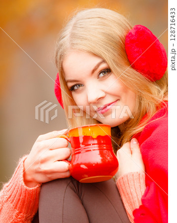 Girl in autumn park enjoying hot drink 128716433