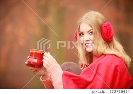 Girl in autumn park enjoying hot drink Girl in autumn park enjoying hot drink 128716434