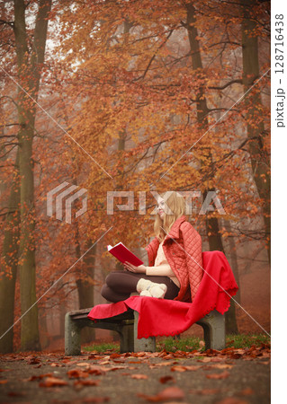 Blonde girl reading book in autumn scenery Blonde girl reading book in autumn scenery 128716438
