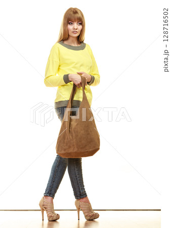 woman holds brown fringe handbag 128716502