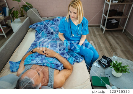 Caring nurse attends to patient in cozy bedroom setting 128716536
