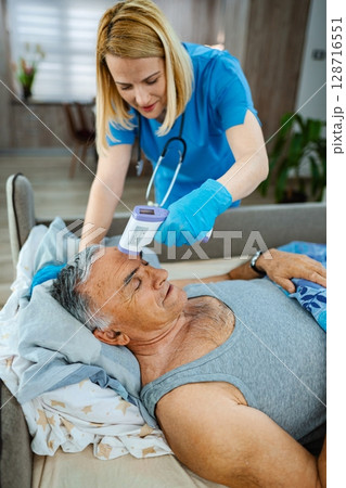 Nurse carefully monitors health of senior man in bed 128716551