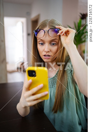 Surprised girl discovers unexpected news while using her smartphone Surprised girl discovers unexpected news while using her smartphone 128716572