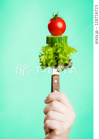 Stack of vegetales on knife in hand 128716723