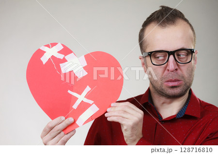 Funny man holds broken heart Funny man holds broken heart 128716810