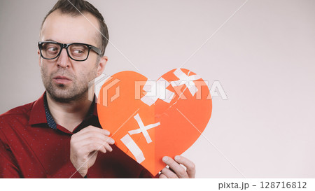 Thoughtful man holds broken heart 128716812