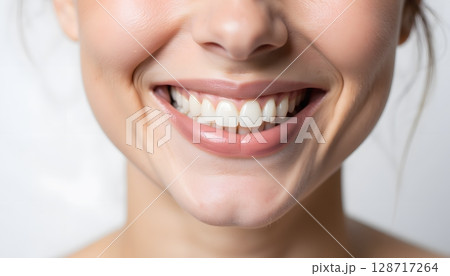 Close-Up Portrait of a Young Woman with Bright Smile Showing Healthy Teeth and Radiant Skin 128717264