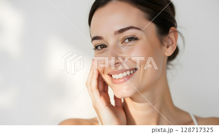 Bright and Radiant Woman Smiling with Healthy Skin in Soft Natural Light Setting 128717325
