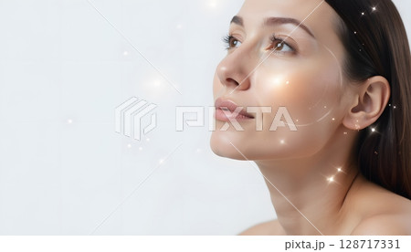 Young woman admiring her reflection with glowing skin and soft sparkle effects glowing around her 128717331
