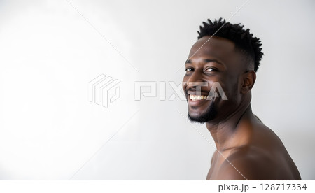 Happy young man smiling brightly against a plain white background showcasing joy and positivity 128717334