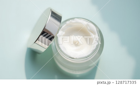 Luxurious White Cream in Open Jar on Soft Blue Surface for Beauty and Skincare Aesthetics 128717335