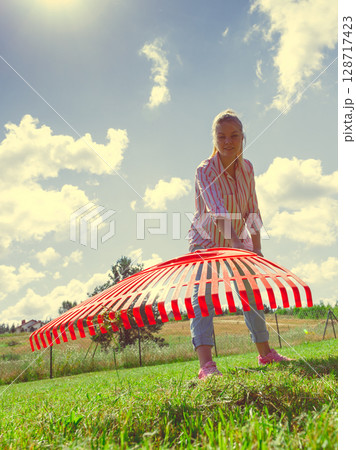 Unusual angle of woman raking leaves 128717423