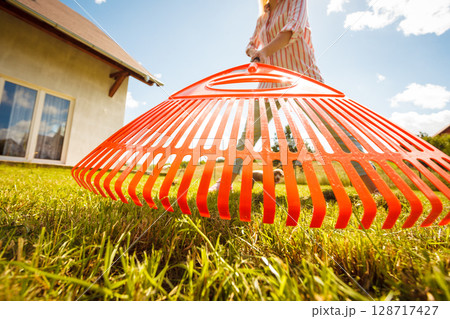 Unusual angle of woman raking leaves 128717427