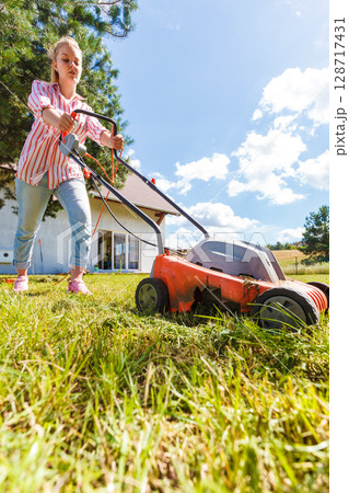Woman mowing green grass 128717431
