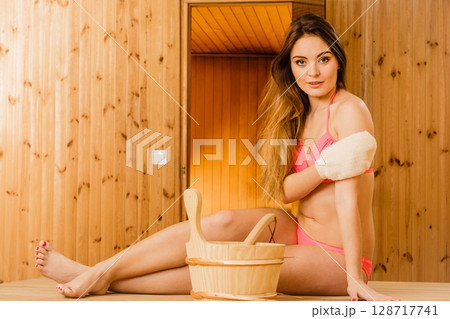 Woman in sauna with exfoliating glove. Skincare. 128717741