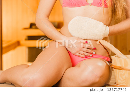 Closeup of woman in sauna with exfoliating glove. 128717743