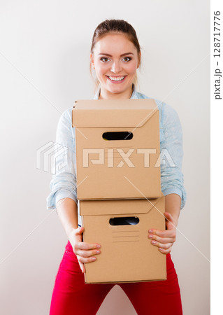 Happy woman moving into house carrying boxes. Happy woman moving into house carrying boxes. 128717776