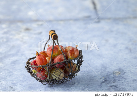 Freshly picked gooseberries resting in a small metal basket 128717973
