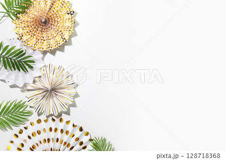 Holidays background with holiday paper decoration and palm leaves on a white background with copy space. Party, carnival or festival background. Birthday or wedding concept. Flat lay 128718368