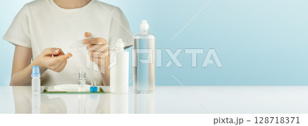 Night Contact Lens Care. Ophthalmology banner, boy clean contact lenses with cleansing solution. Concept of eye care and good vision. Mockup of multipurpose solution for lenses. Soft focus, copy space Night Contact Lens Care. Ophthalmology banner, boy clean contact lenses with cleansing solution. Concept of eye care and good vision. Mockup of multipurpose solution for lenses. Soft focus, copy space 128718371