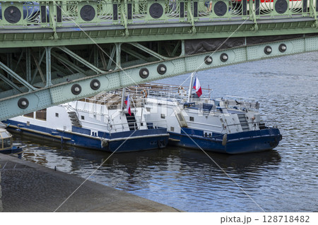 Two tour boats moored on the Vltava River under the Cechuv most bridge in Prague 128718482