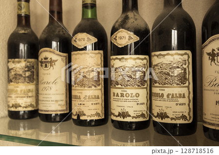 Dusty bottles of vintage Barolo wine aging on a glass shelf Dusty bottles of vintage Barolo wine aging on a glass shelf 128718516