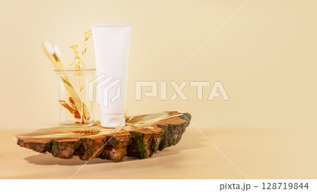 Organic oral care products set. Eco friendly still life with bio toothpaste, toothbrushes in a glass jar on wooden podium with copy space. Natural teeth hygiene concept. Mockup for toothpaste 128719844