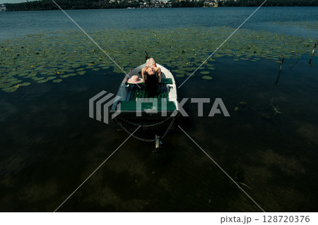 The girl sits in a boat in the middle of the lake 128720376