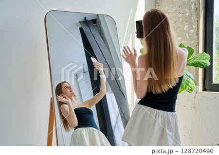 Smiling young teenage female taking selfie photo on smartphone 128720490
