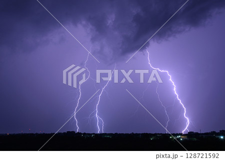 Multiple lightning bolts striking during dramatic night thunderstorm. 128721592