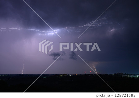 Horizontal lightning flashes across a purple night sky Horizontal lightning flashes across a purple night sky 128721595