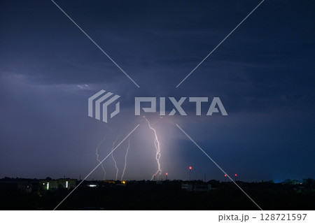 Multiple lightning bolts striking during dramatic night thunderstorm. 128721597