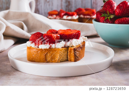 Grilled toast with cream cheese and stewed strawberries on a plate on the table 128721650
