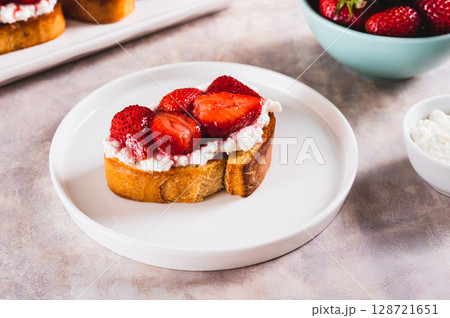Sweet toast with ricotta and strawberry jam on a plate on the table 128721651