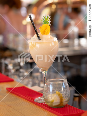 Frozen tropical cocktail with pineapple decoration and lemon wedges 128722586