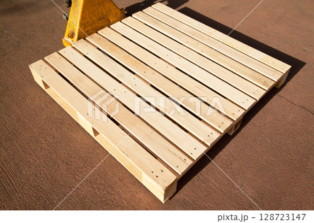 Empty wooden pine pallet with a pallet truck or transpallet in front of a warehouse, logistics and industrial transportation 128723147