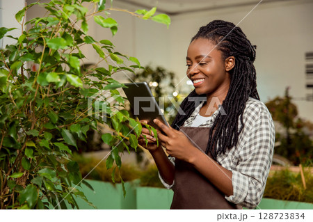 Flower shop assistant making pictures of plant and smiling 128723834