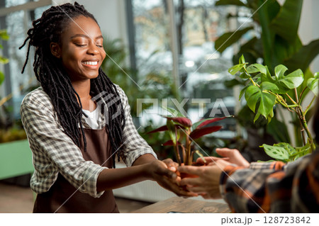Flower shop assistant selling flower to the customer and smiling nicely 128723842