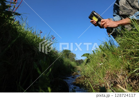 A person is holding a device in a field with a blue sky in the background A person is holding a device in a field with a blue sky in the background 128724117
