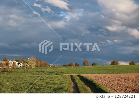 Cloudy sky with a house in the distance Cloudy sky with a house in the distance 128724221