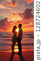Couple embracing during sunset on a beach with beautiful clouds and ocean waves 128724602