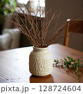 Decorative vase with dry branches on a wooden table in a cozy indoor setting 128724604